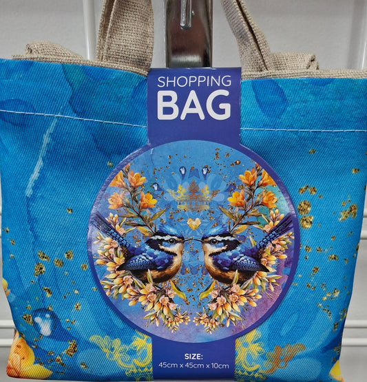 Blue shopping bag with nature-themed design and 'Shopping Bag' text, hanging on a metal rack.