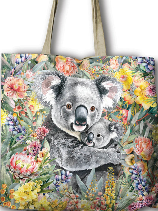 Tote bag with a design of a koala and baby surrounded by flowers, held by a hand against a white background.