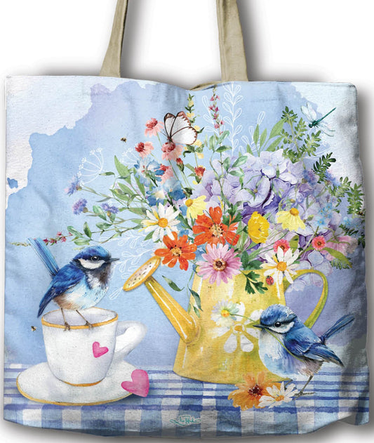 Tote bag with floral design and birds, held by a hand against a white background.